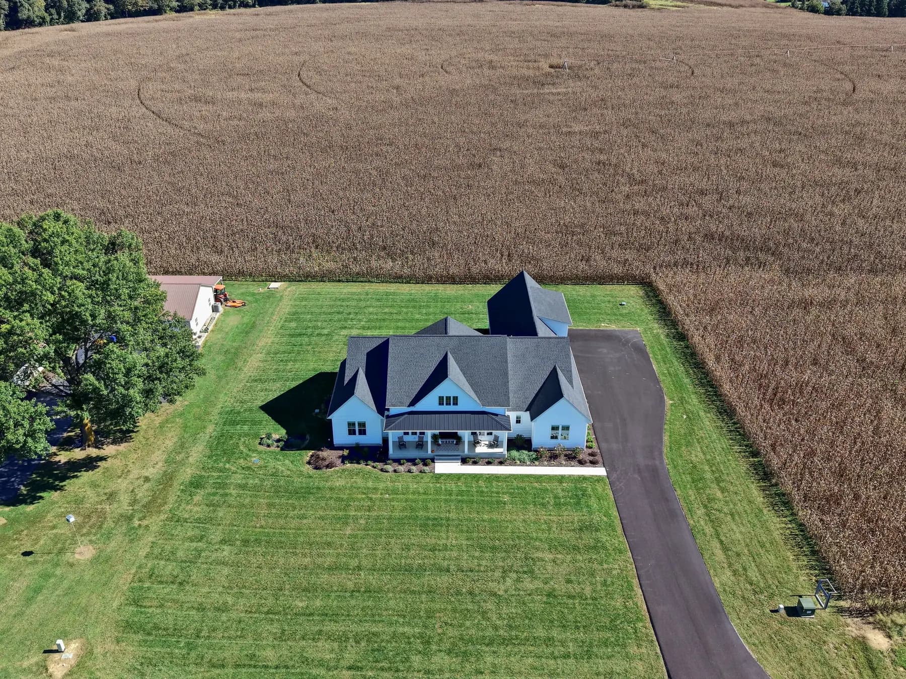 The house from high above, on its lawn between a corn field and a tree line